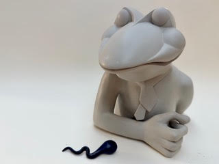 Amphibien à deux têtes Une sculpture d'une grenouille avec un corps humanoïde, regardant un serpent.