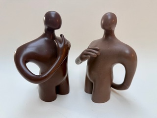 Hommes discutant Deux sculptures stylisées représentant des figures humaines aux formes rondes.