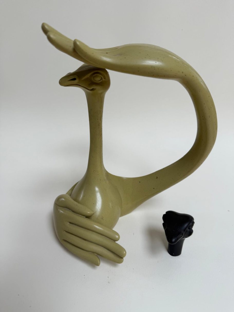 Autruche beige Sculpture en forme d'oiseau, avec une main stylisée et un embout noir à côté.