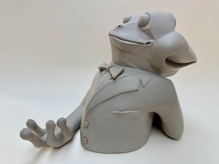 Amphibien à deux têtes Figurine en argile représentant un personnage avec un costume et une expression amicale.
