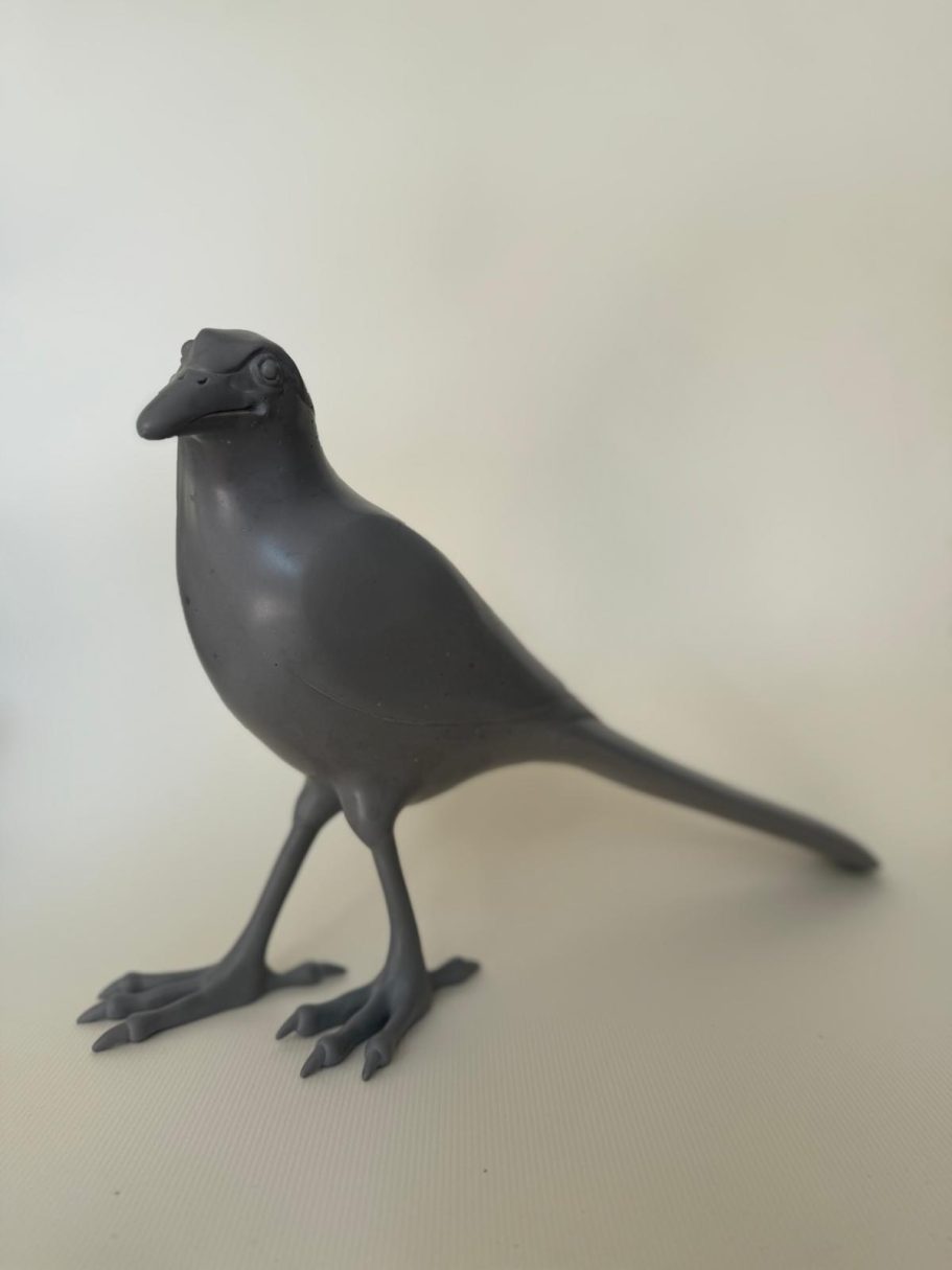 Pie Grise Oiseau en résine noir sur fond clair, debout avec un corps élancé et des pattes fines.