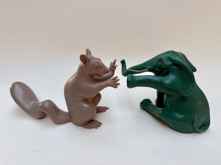 Écureuil et éléphant joueur Un écureuil brun et un éléphant vert en plastique se font face.